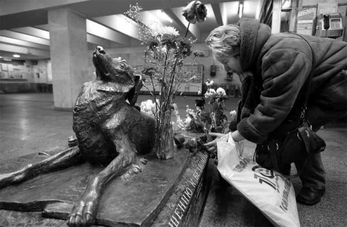 Sieviete noliek ziedus pie ielu suņa Maļčika pieminekļa Mendeļejeva metro stacijā Maskavā (Foto - LETA/ImageForum)