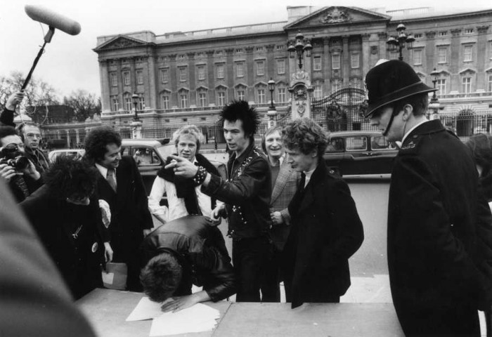 Pēc ierakstu kompānijas EMI atteikšanās izdot viņu albumu 1977. gada 10. martā Sex Pistols Bekingemas pils priekšā paraksta līgumu ar A&M Records. Tiesa, arī šis līgums tiks lauzts jau pēc nedēļas. Otrais no labās – Malkolms Maklarens, ceturtais – Sids Višess. ( Foto: Getty Images)